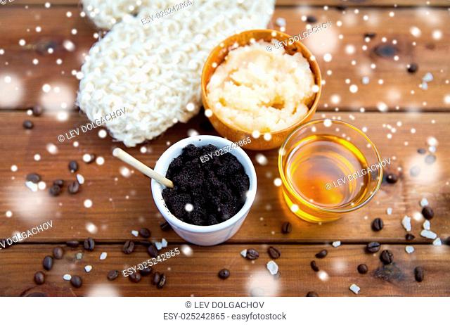 beauty, spa, bodycare, bath and natural cosmetics concept - coffee scrub in cup with honey and wisp on wooden table over snow