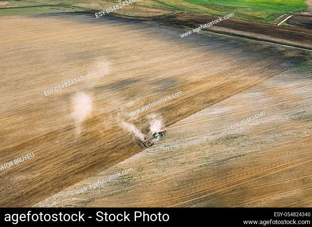 Aerial View. Tractor Plowing Field In Spring Season. Beginning Of Agricultural Spring Season. Cultivator Pulled By A Tractor In Countryside Rural Field...