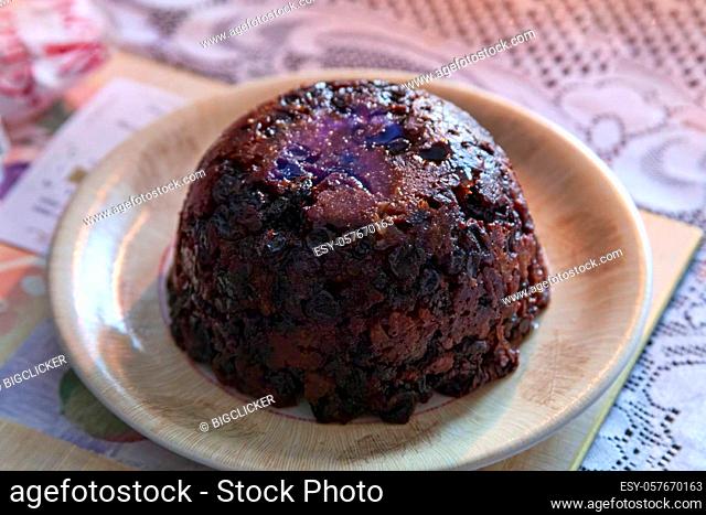Christmas pudding dessert lit with a burning brandy flame served at dinner time on Christmas day during the festive season in December stock photo image