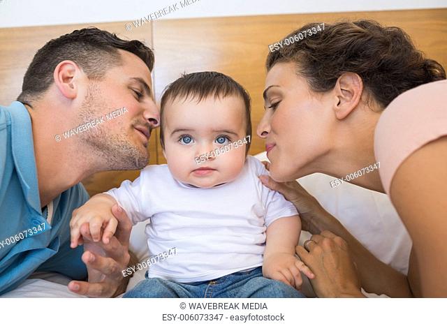 Parents kissing baby on cheek