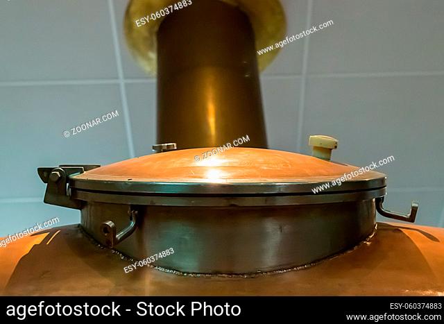 copper hatch on a large tank on the background of a pipe leaving the white ceiling