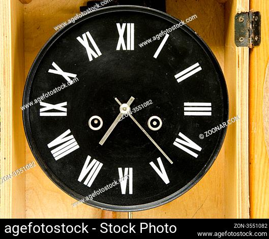 Ancient black clock with roman numbers and arrows. Antique clock in wooden box