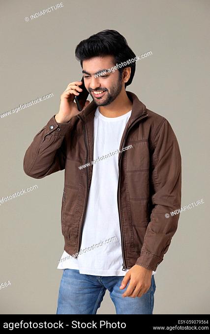 A YOUNG MAN HAPPILY TALKING ON MOBILE PHONE