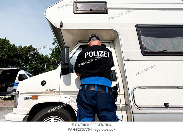 A police officer inspects a camper van by the A5 highway near Neuenburg,  Germany, 22 July 2016. Because many campers and trailers are overloaded during summer