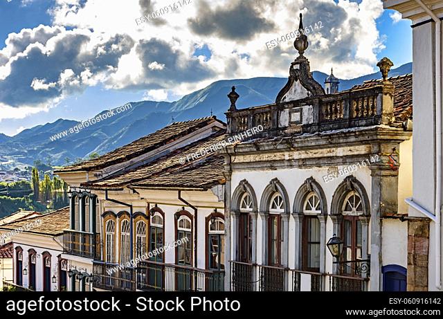 Facade of old houses built in colonial architecture with their balconies, roofs and colorful details with the mountains in the background in the historical city...