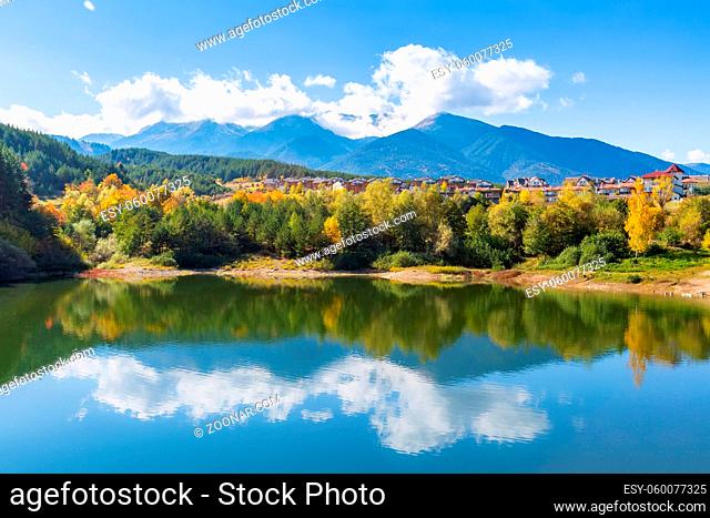 Bansko, Bulgaria autumn panorama background of Pirin mountain peaks, lake water, colorful green, red and yellow trees reflection