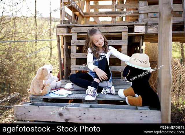 Girl playing with her teddy bears at tree house