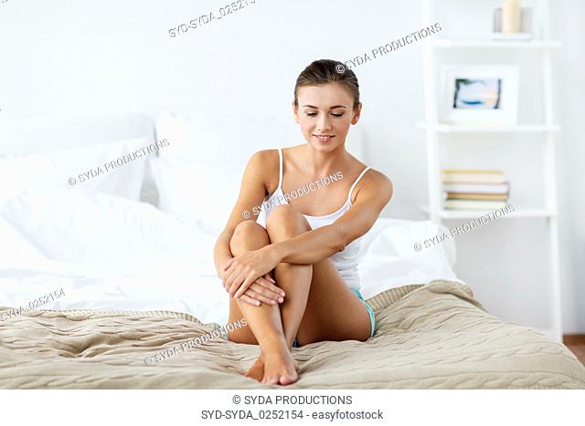 beautiful woman with bare legs on bed at home
