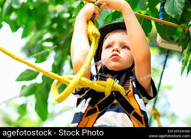 Girl climbing in adventure park is a place which can contain a wide variety of elements, such as rope climbing exercises, obstacle courses and zip-lines