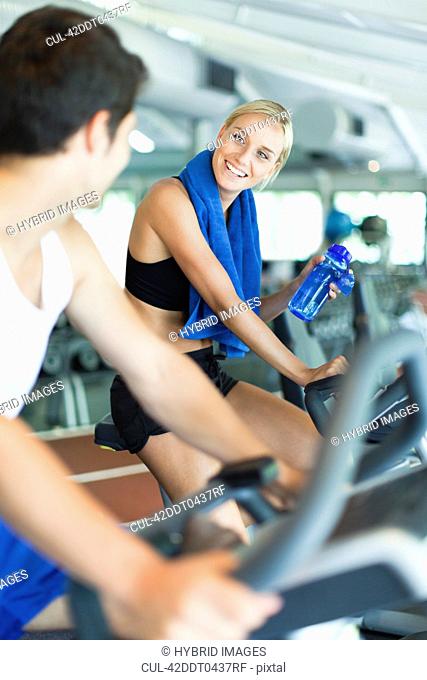 Couple using exercise machines in gym