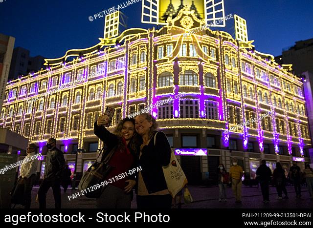 08 December 2021, Brazil, Curitiba: Tourists take photos in front of the Christmas decorations of the Palacio Avenida...The Palacio Avenida is one of the most...