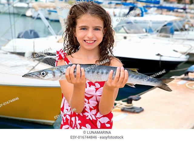 Happy kid fisherwoman with barracuda fish catch in Mediterranean marina