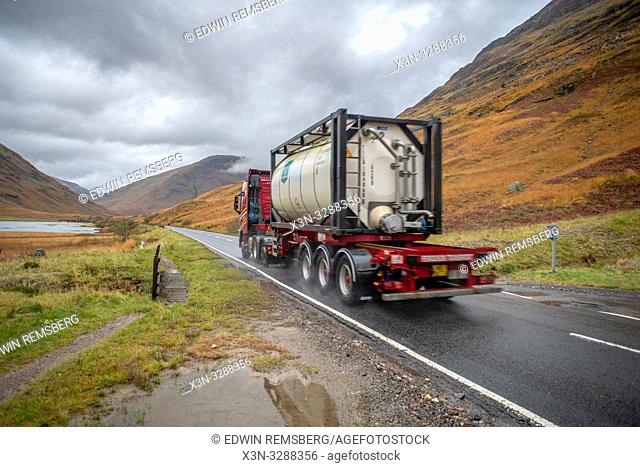 A truck drives on a road near Three Sisters of Glen Coe in Glen Coe, Scotland