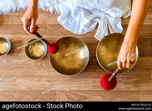 Therapist playing brass singing bowl with mallet on floor