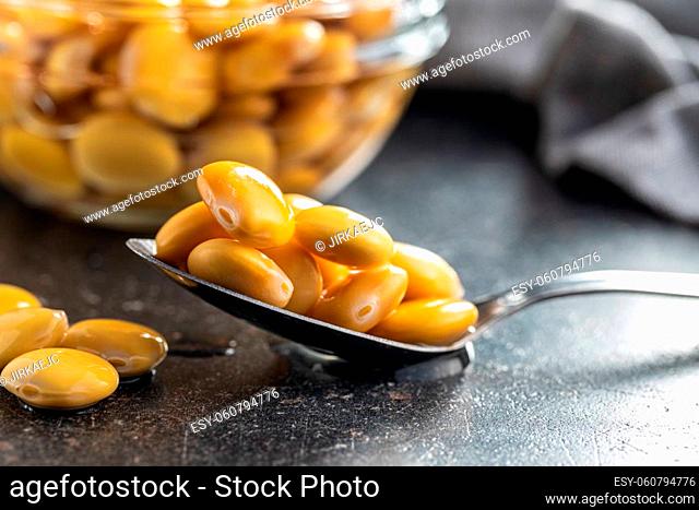 Pickled yellow Lupin Beans in spoon on kitchen table