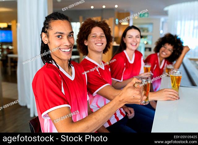 Diverse group of male and female sports fans having beer watching game at bar