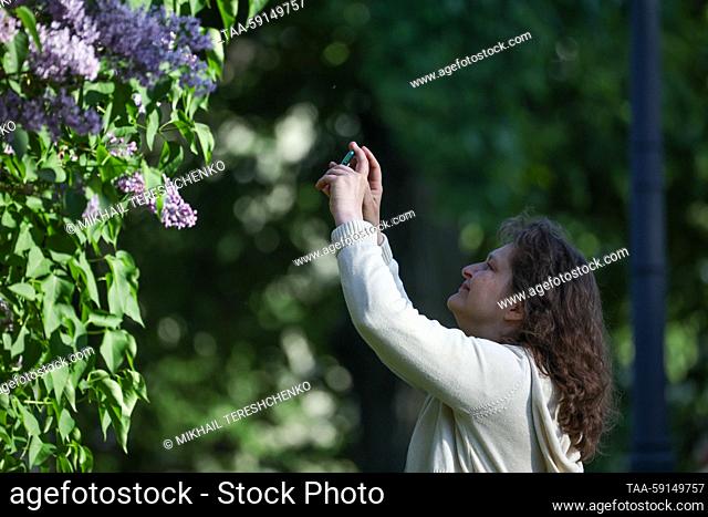 RUSSIA, MOSCOW - MAY 17, 2023: A woman take a picture of a blooming lilac tree at the Kolomenskoye Museum-Reserve. Mikhail Tereshchenko/TASS