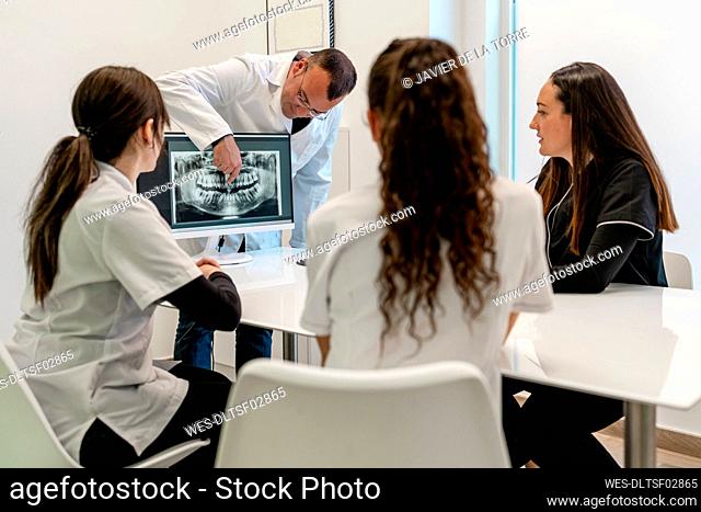 Dentist explaining x-ray with nurses at desk in clinic
