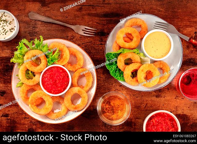 Calamari rings. Deep fried squid rings with wine and various dips, overhead flat lay shot on a dark rustic wooden background