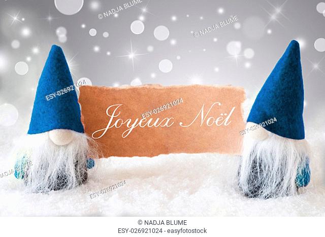 Christmas Greeting Card With Two Blue Gnomes. Sparkling Bokeh And Noble Silver Background With Snow. French Text Joyeux Noel Means Merry Christmas
