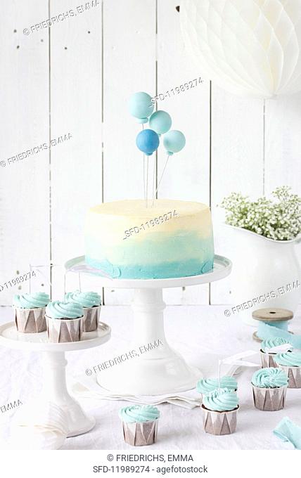 An ombre cake with balloons and chocolate cupcakes