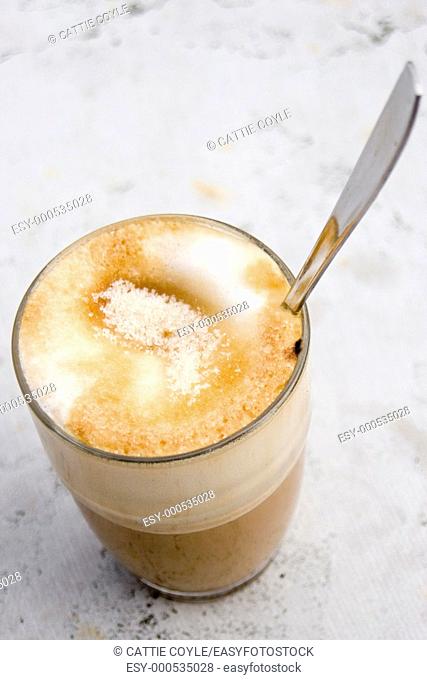 A glass of Caffe Latte with sugar on top