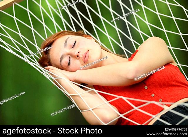 Woman relaxing sleeping on rope hammock in a garden or forest