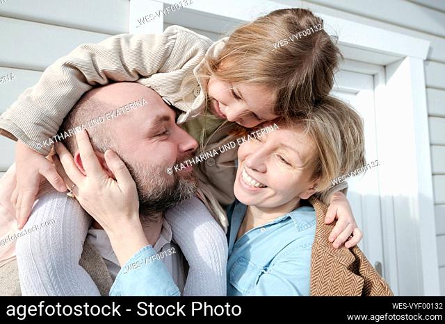 Happy family hugging in front of their house