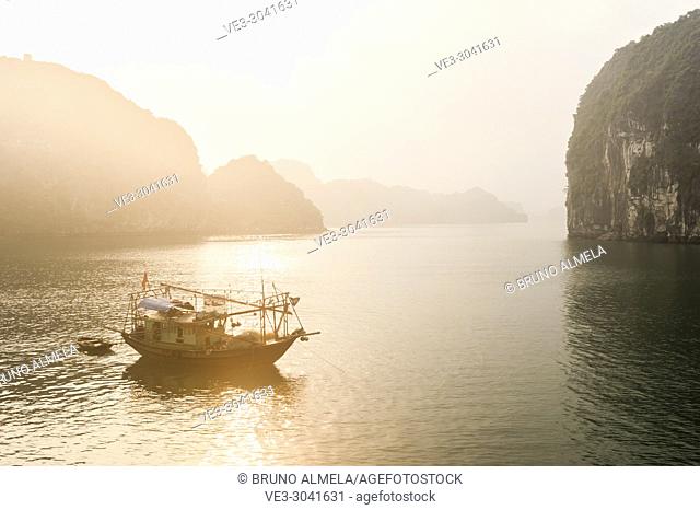Sunrise over fishing boat in the karst landscape of Ha Long Bay, Quang Ninh Province, Vietnam. Ha Long Bay is a UNESCO World Heritage Site