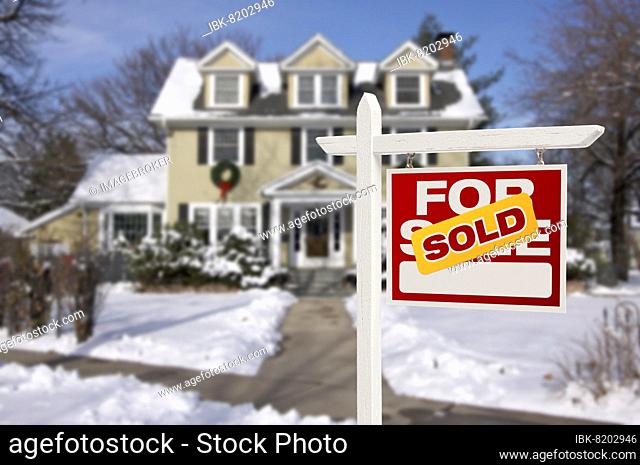 Sold home for sale real estate sign in front of beautiful new house in the snow