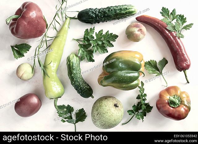On the table and on a napkin a variety of ripe vegetables: tomatoes, peppers, cucumbers, parsley, zucchini. Top view with copy space. Flat lay
