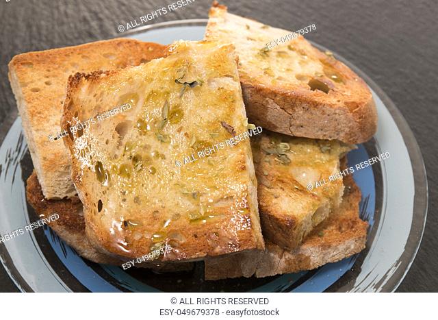 Traditional Portuguese bread toasted with virgin olive oil and oregano herbs on a shale stone