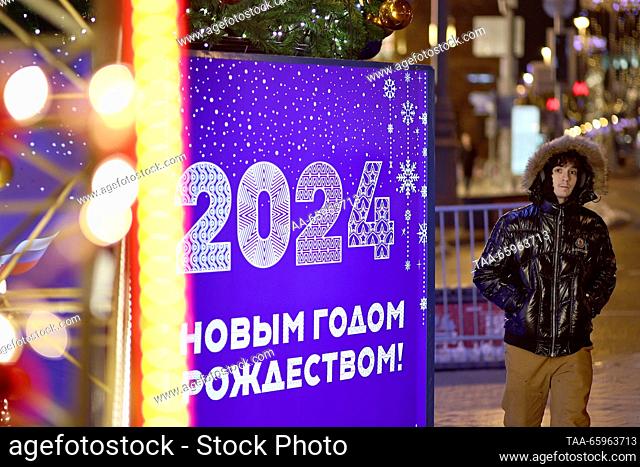 RUSSIA, MOSCOW - 21 de diciembre de 2023: Un hombre pasa por un cartel de la calle de Navidad. Mikhail Tereshchenko/TASS
