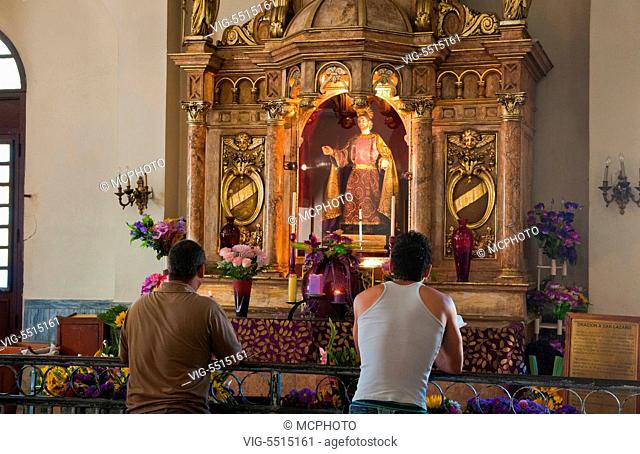 Men praying inside of Santuary of St Lazaro church in Santiago de Las Vegas Cuba - 07/04/2015