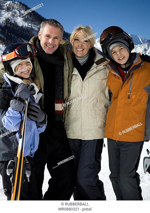 Portrait of a mid adult couple and their children holding skis