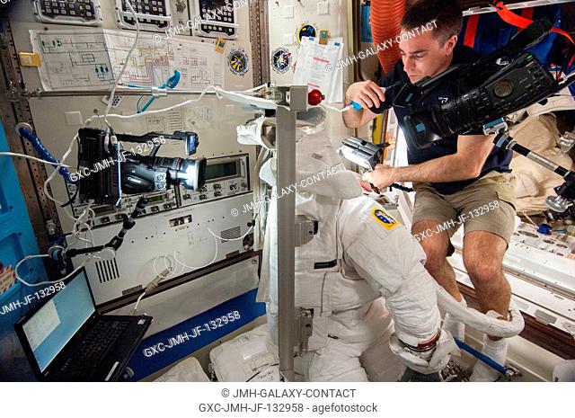 NASA astronaut Chris Cassidy, Expedition 36 flight engineer, works on an Extravehicular Mobility Unit (EMU) spacesuit in the Quest airlock of the International...