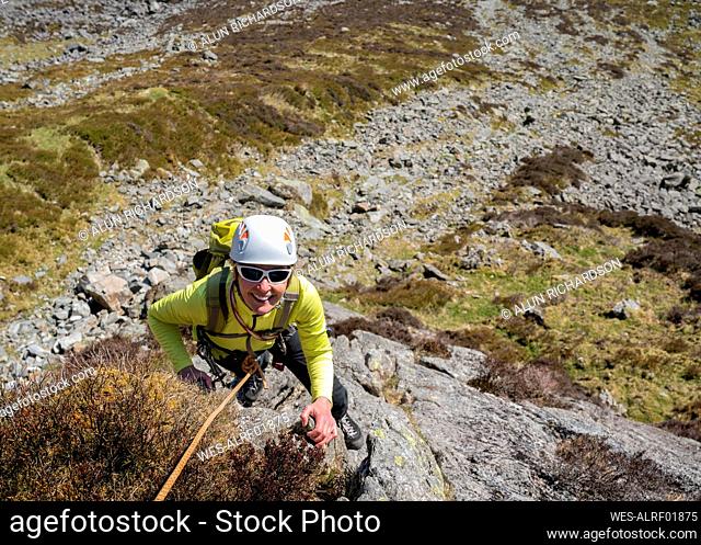 Happy senior woman climbing rock mountain