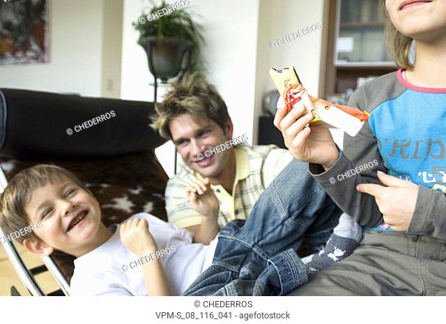 Sister sitting holding an ice-cream with her brother and father
