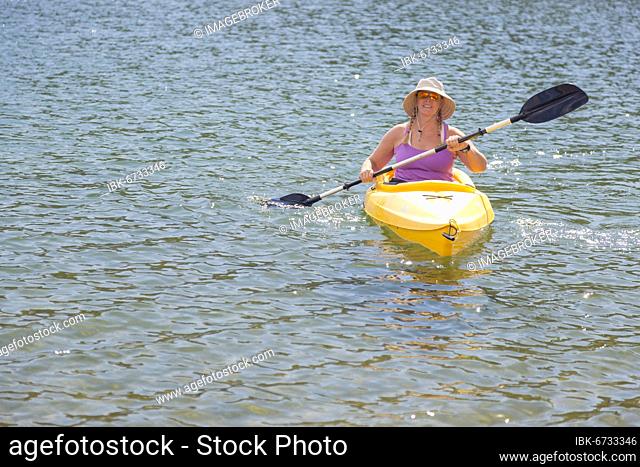 Woman kayaking on beautiful peaceful mountain lake