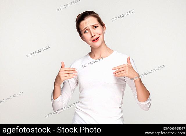 Puffy funny woman pointing hands himself and looking at camera. Studio shot, gray background