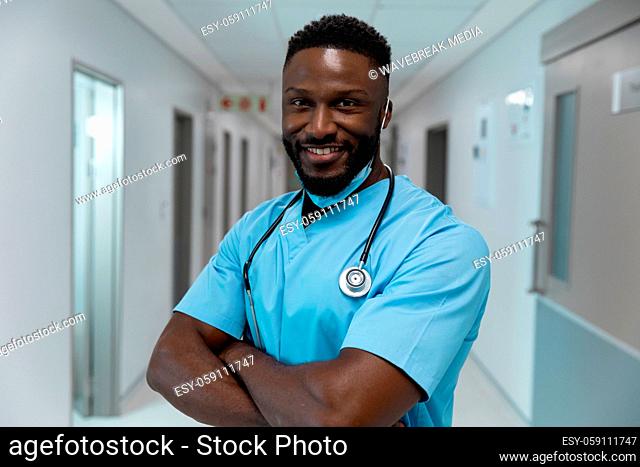 Portrait of african american male doctor wearing face mask standing in hospital corridor
