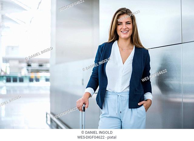 Portrait of smiling young businesswoman with luggage