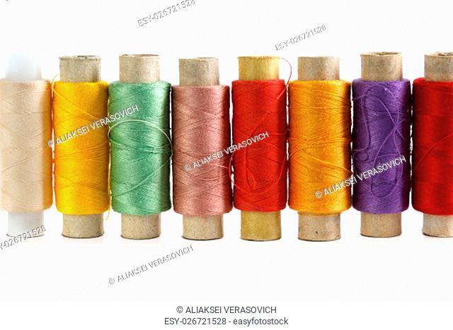 Several spools of brightly colored threads on a white background