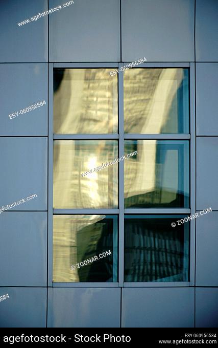 Abstrakte Spiegelungen in quadratischen Fenstern an einer markanten Fassade aus Blechplatten