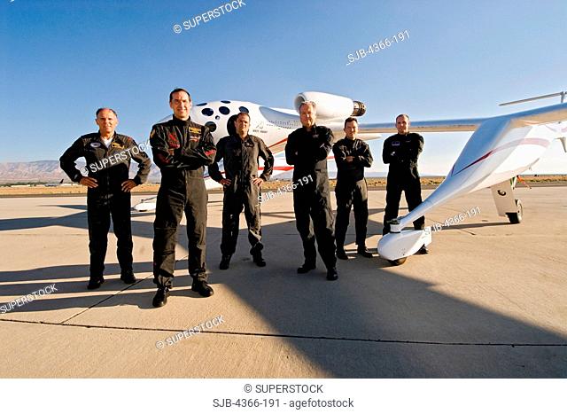 The six test pilots of Scaled Composites stand with White Knight One on the ramp at Mojave Airport in Mojave, California