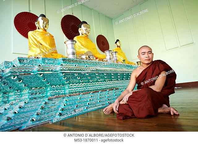 A burmese buddhist monk sit in a praying room inside the Shwedagon Pagoda complex  Yangon  Myanmar
