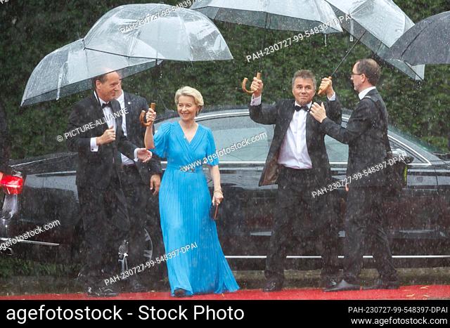 25 July 2023, Bavaria, Bayreuth: Ursula von der Leyen (CDU), President of the EU Commission, and husband Heiko (l) arrive in the rain for the opening of the...
