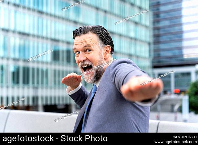 Carefree mature businessman having fun gesturing in front of building