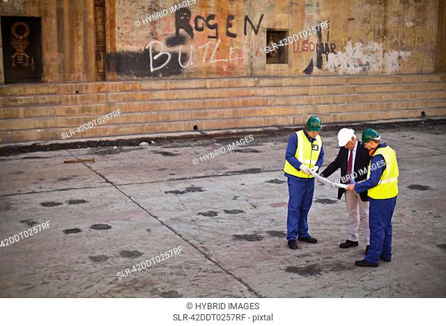 Workers reading blueprints on dry dock