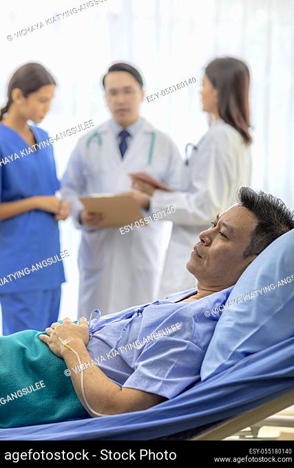 Worried patient in bed with professional team doctors in background